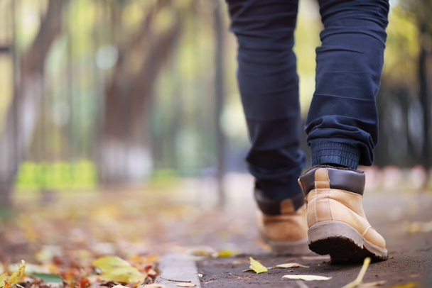 Φθινοπωρινή ιδέα Πεζοί στα πόδια στο δρόμο. Φθινοπωρινά φύλλα στο μονοπάτι. - Φωτογραφία, εικόνα