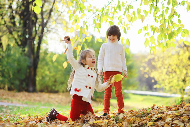 Enfants pour une promenade dans le parc d'automne. Les feuilles tombent dans le parc. La famille. Tomber. Le bonheur. - Photo, image