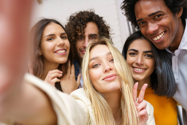 Multi-etnische groep van vrienden het nemen van een selfie samen terwijl het hebben van plezier buiten. - Foto, afbeelding