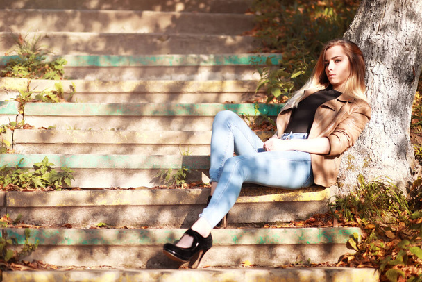 Młoda piękna dziewczyna na spacerze w jesiennym parku. Spadek liści w parku miejskim. październik. - Zdjęcie, obraz