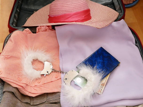 подорожня валіза, сонячний капелюх, білизна та наручники для дорослих ігор на дерев'яному фоні, бізнес-концепція секс-туризму. бдсм, вид зверху
 - Фото, зображення