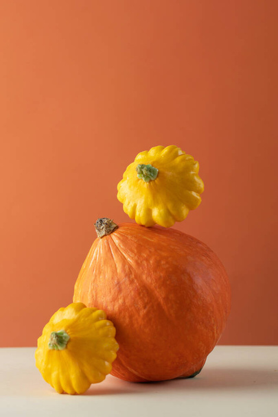 Still life of a balance of pumpkins and patisson on an orange background. The concept of autumn, Thanksgiving. - Foto, Imagem