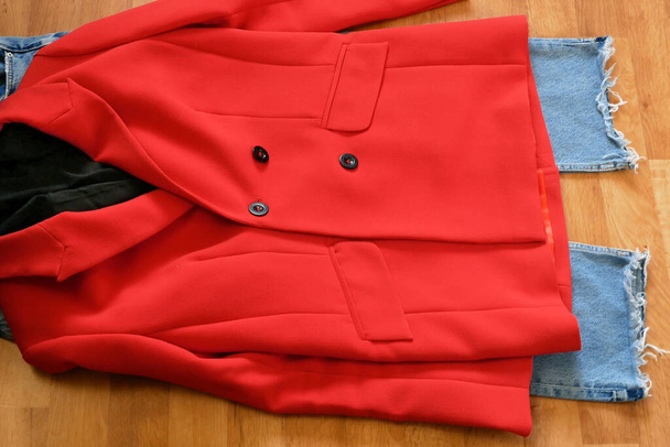 woman makes modern outfit with red jacket and blue jeans, top view - Photo, Image