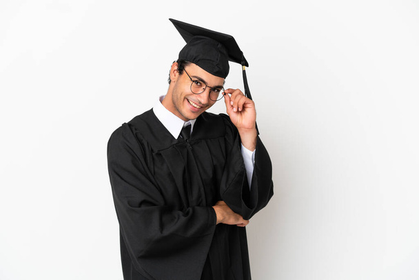 Mladá univerzita absolvent přes izolované bílé pozadí s brýlemi a šťastný - Fotografie, Obrázek