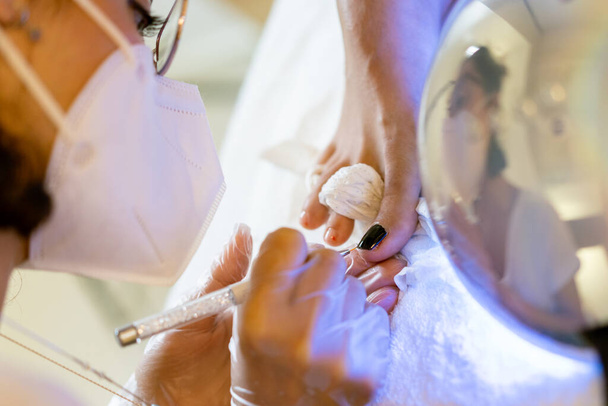 Косметолог дає педикюр, малюючи нігті своїх клієнтів в центрі краси
. - Фото, зображення