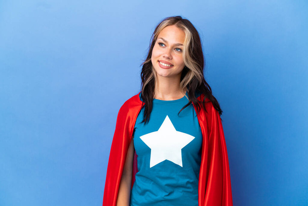 Super Hero Teenager girl isolated on blue background looking to the side and smiling - Foto, immagini