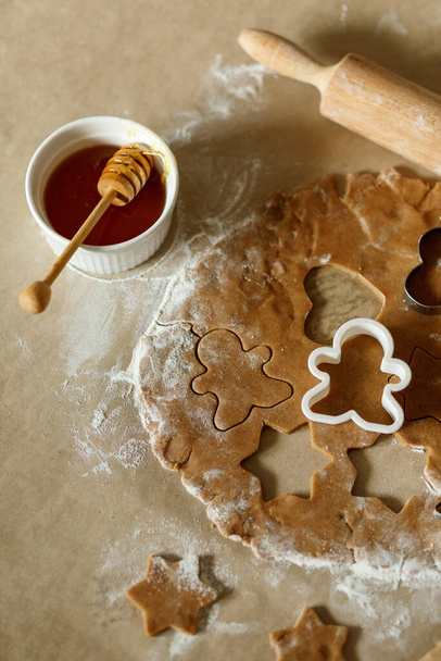 Χριστουγεννιάτικα γλυκά. ζύμη για μπισκότα με μελόψωμο. φόρμα ψησίματος στο τραπέζι με μέλι και κουνιστή ζύμη. - Φωτογραφία, εικόνα