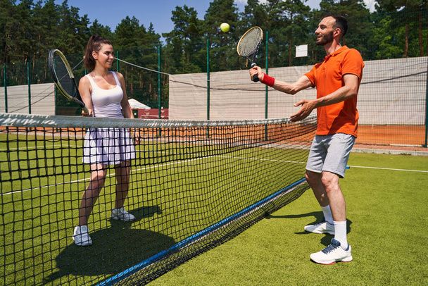 Joyous cute sportsman serving the ball to his tennis partner - Foto, Imagem