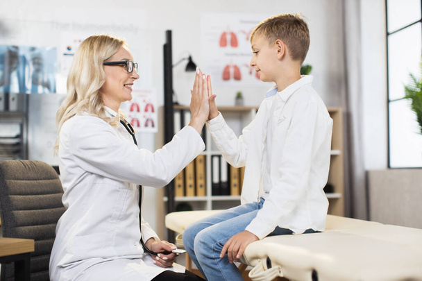 Caucasian boy giving high five to pleasant female doctor - 写真・画像