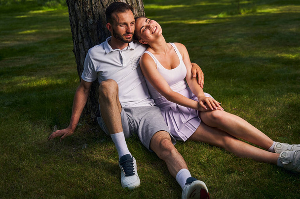 Loving attractive couple seated by a tree - Foto, immagini