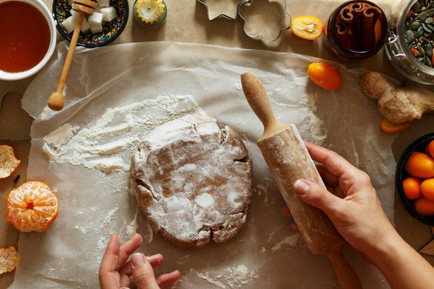 Домашнее приготовление рождественского хлеба в разной форме на коричневом фоне. Руки держат режущие звездочки в тесте для печенья.  - Фото, изображение