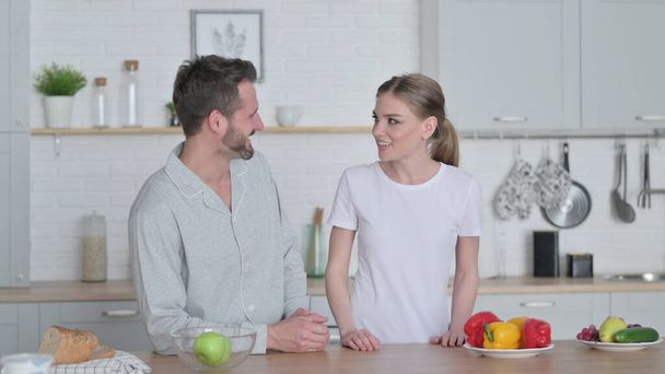 Ευτυχισμένο ζευγάρι μιλάει ενώ στέκεται στην κουζίνα  - Φωτογραφία, εικόνα