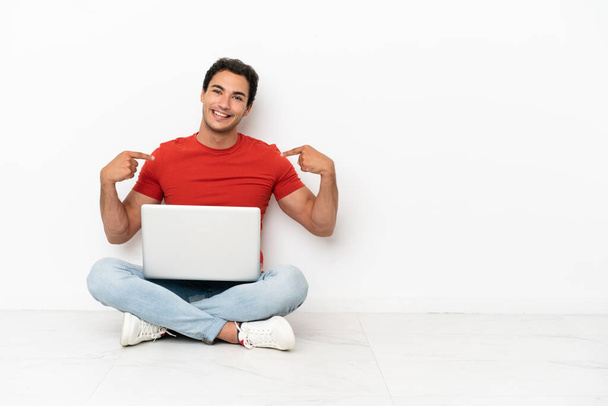 Caucasico bell'uomo con un computer portatile seduto sul pavimento orgoglioso e soddisfatto di sé - Foto, immagini