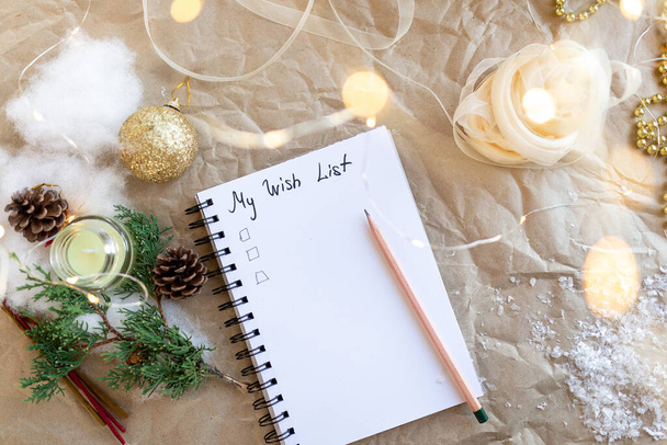 İçinde 2022 istek listemin olduğu bir not defteri. Altın Noel süsü, yeni yıl ışıkları, kurdele, köknar dalı. Yeni yıl ve hediye planlama konsepti. Flatlay. Üst görünüm. - Fotoğraf, Görsel