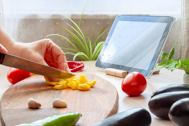Kobieta ogląda online klasy kulinarne na tablecie, gotowanie sałatki ze świeżych warzyw. Żywność wegetariańska. - Zdjęcie, obraz