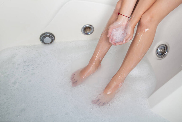 Καλά καλλωπισμένα γυναικεία πόδια σε αφρό μπάνιου.  - Φωτογραφία, εικόνα