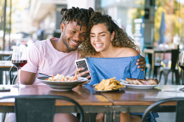 Couple using a mobile phone at a restaurant. - Fotó, kép