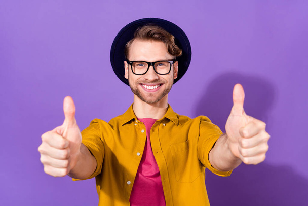 Foto de atractivo alegre joven alegre mostrar pulgares arriba consejo anuncio aislado sobre fondo de color violeta - Foto, imagen