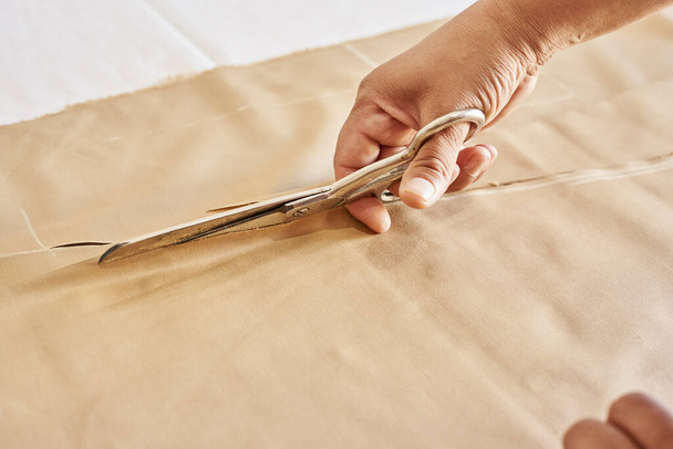 A dressmaker cutting cloth with scissors in a tailor studio - Foto, Imagem
