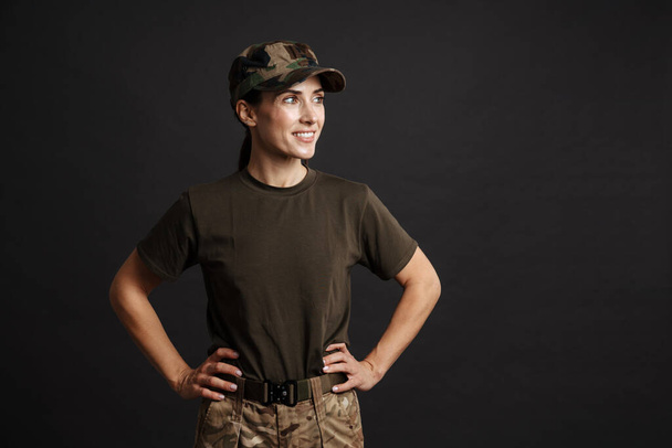 Szczęśliwy piękny żołnierz kobieta uśmiecha się i patrząc na bok odizolowany na czarnym tle - Zdjęcie, obraz