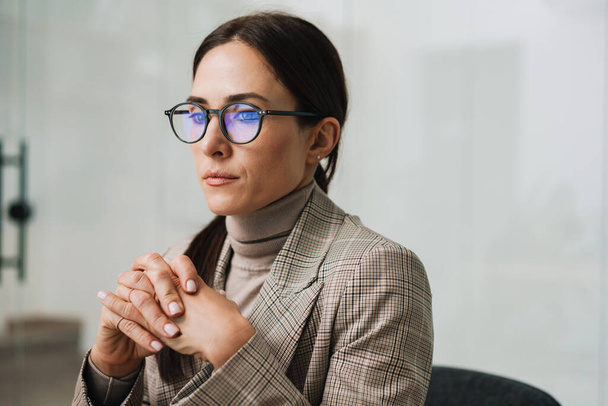 Focused charming woman in eyeglasses thinking while working in office - Foto, Bild