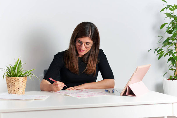 Illustrator vrouw tekent schetsen zittend aan haar bureau - Foto, afbeelding