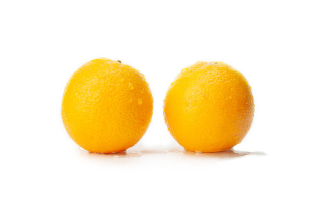 A closeup shot of two newly washed oranges with water on them on an isolated background - Фото, изображение
