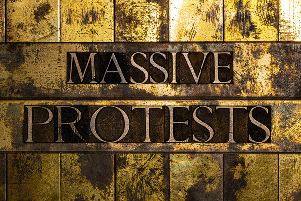 Protestas masivas mensaje de texto sobre texturas de cobre grunge y fondo de oro vintage - Foto, Imagen