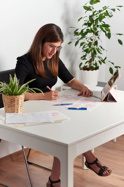 Εικονογράφος γυναίκα σχεδιάζει σχέδια κάθεται στο γραφείο της - Φωτογραφία, εικόνα