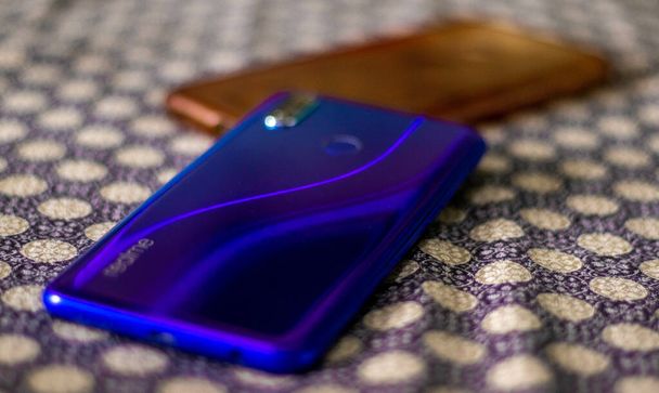 КАРАЧИ, ПАКИСТАН - 24 июня 2021 года: селективный фокус на голубом смартфоне Realme 3 Pro с футляром на чехле для кровати - Фото, изображение