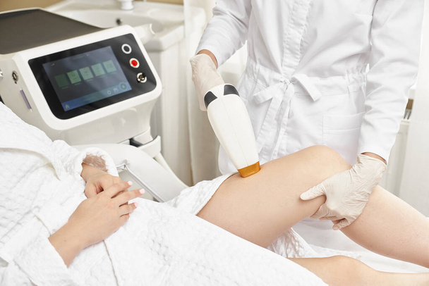 Young woman making body hair removal laser depilation in beauty center - Valokuva, kuva