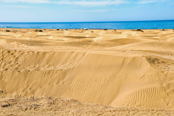 A shot of the golden sand under a blue sky and an ocean in t background. - Photo, Image