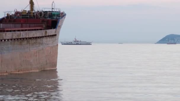 A kikötőben horgonyzó hajó és a tengeren közlekedő személyszállító komp látképe - Felvétel, videó