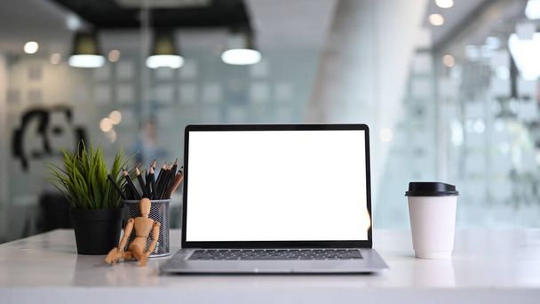 Εμπρόσθια όψη του mock up laptop του υπολογιστή ehh κενή οθόνη, φλιτζάνι καφέ, φυτό και μολυβοθήκη σε λευκό τραπέζι. - Φωτογραφία, εικόνα
