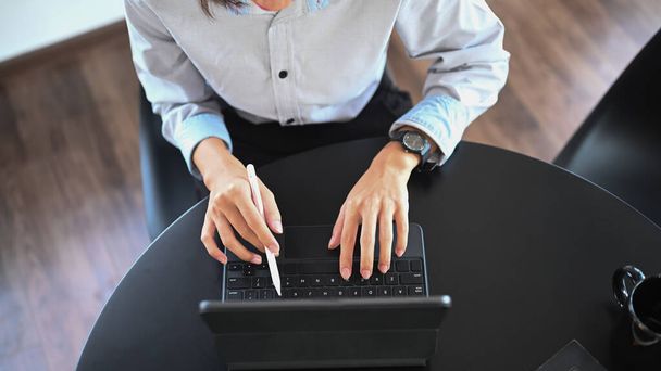 Άνω όψη του γυναικείου υπαλλήλου που εργάζεται με ταμπλέτα υπολογιστή στο γραφείο. - Φωτογραφία, εικόνα