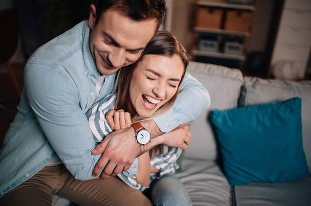 Portrait of a young couple in casual clothes on the couch in hugging each other - Photo, Image