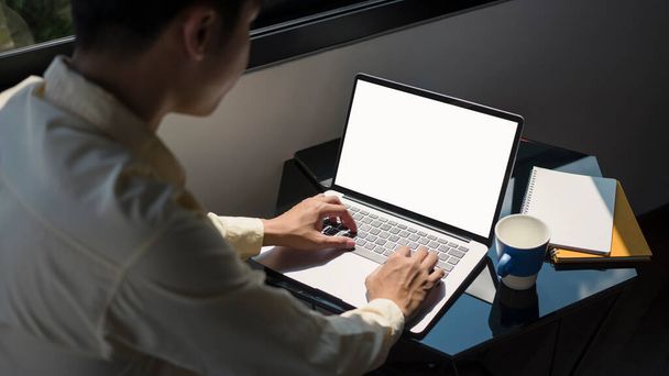 Widok boczny koncentratu biznesmena pracującego na laptopie komputerowym w biurze. - Zdjęcie, obraz