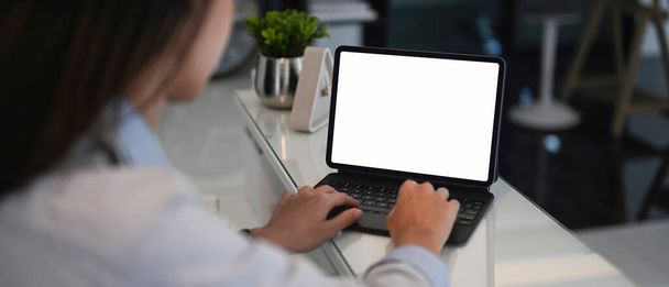 Vista da vicino sulla spalla della giovane imprenditrice che lavora su tablet per computer in un ufficio moderno. - Foto, immagini
