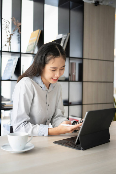 Портрет счастливая женщина сотрудник улыбается и работает на компьютере планшет в современном офисе. - Фото, изображение