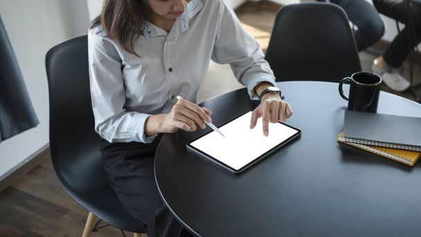 Snímek mladé zaměstnankyně sedící v kancelářské místnosti a používající digitální tablet. - Fotografie, Obrázek