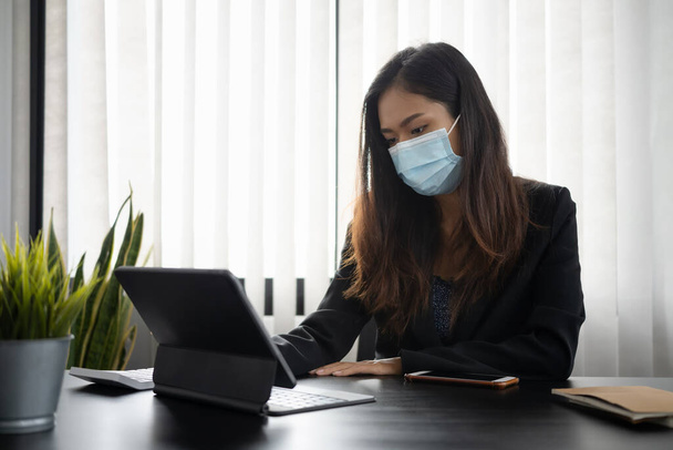 Bizneswoman w masce ochronnej koncentrat pracy na tablecie komputerowym w miejscu pracy hr. - Zdjęcie, obraz