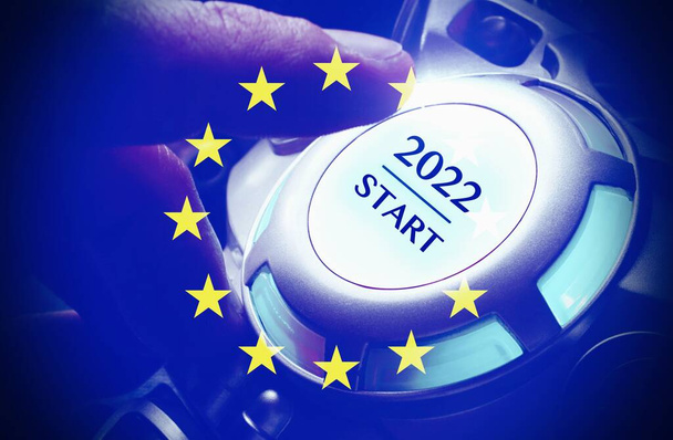 Ludzka ręka wciskająca przycisk startu 2022, z flagą europejską, koncepcja rozpoczęcia nowego roku . - Zdjęcie, obraz