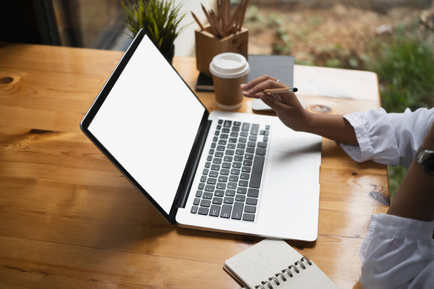 Przycięte ujęcie kobiety freelancer trzymając ołówek i pracując na laptopie komputera w kawiarni. - Zdjęcie, obraz