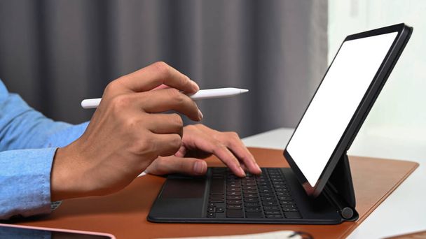 Κοντινό πλάνο χέρι άποψη του επιχειρηματία κρατώντας στυλό που δείχνει στην οθόνη του tablet υπολογιστή. - Φωτογραφία, εικόνα