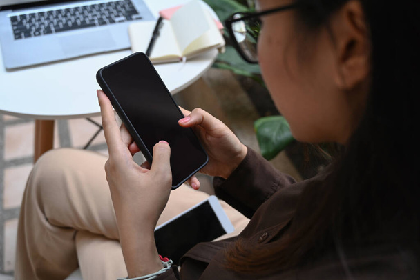 Sobre vista ombro de empresária sentado no café e usando telefone celular. - Foto, Imagem