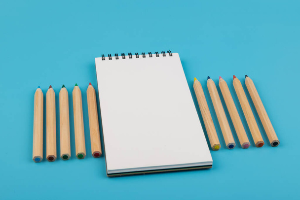 multicolor pencils and blank notebook on blue background with copy space - Φωτογραφία, εικόνα