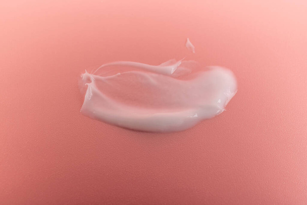 Crème de beauté blanche surligneur lotion frottis tache d'échantillon sur fond de pêche rose - Photo, image