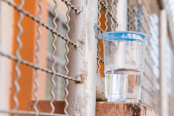 Plastové kelímky s vodou na stěně plotu nebo bariéra z kolejnic - Fotografie, Obrázek