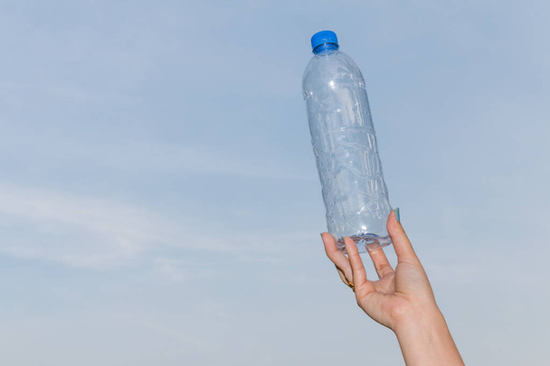 Hand halten Flasche Trinkwasser auf blauem Himmel Hintergrund - Foto, Bild