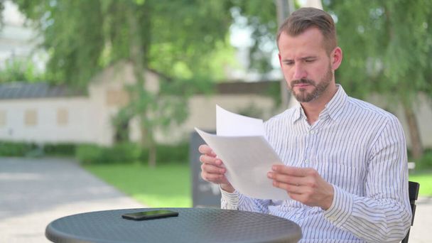 Hombre adulto maduro leyendo documentos en el café al aire libre  - Foto, Imagen